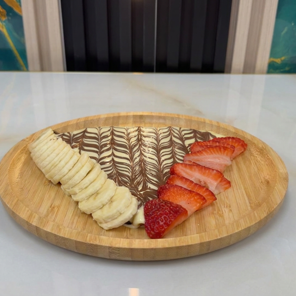 Sliced banana and strawberries arranged around a marbled dessert on a round wooden serving board.
